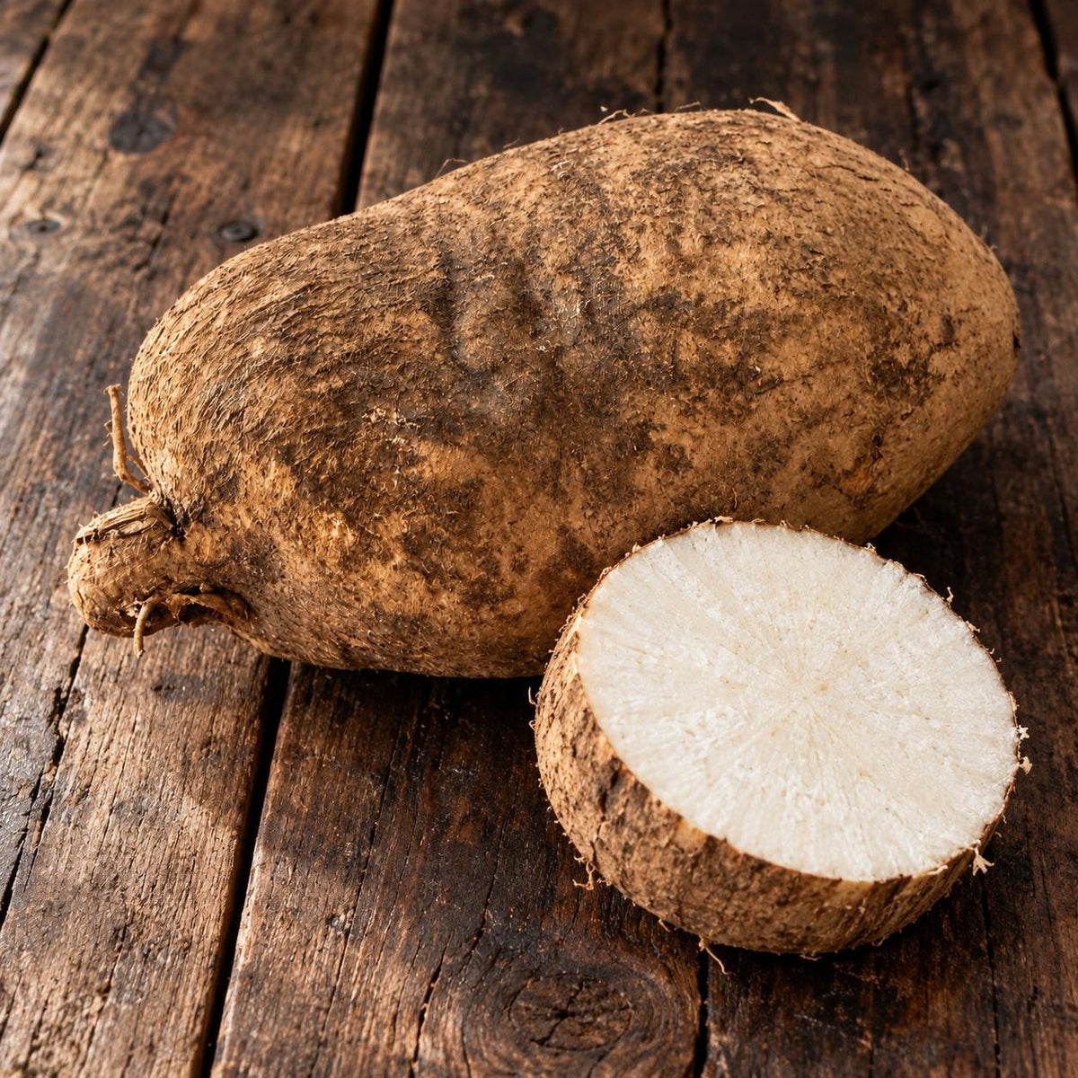 Ñame yam on rustic wood with a cut slice showing white flesh